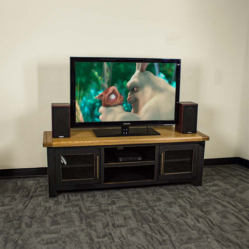 An overall view of the Cascais 2 Door Medium Entertainment Unit. There is a large TV on top with two speakers on either side. There is a DVD player on the top shelf in the middle of the unit.