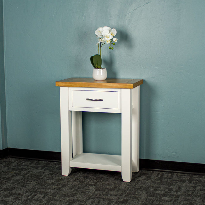 Front of the white Felixstowe Small Pine Hall Table. There is a small pot of white flowers on top.