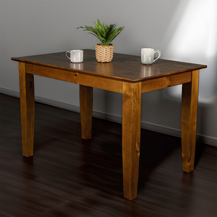 An overall view of the Hamilton Dining Table with Rimu Finish (1200mm), with a potted plant on top and two coffee mugs.