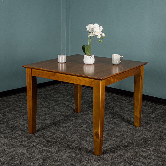 Front of the Hamilton Square Pine Dining Table (1m). There are two coffee mugs and a pot of flowers on top.