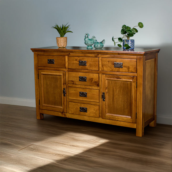 Front view of the Montreal Rimu Stained Buffet/Sideboard, there are two blue glass ornaments and two potted plants on top.