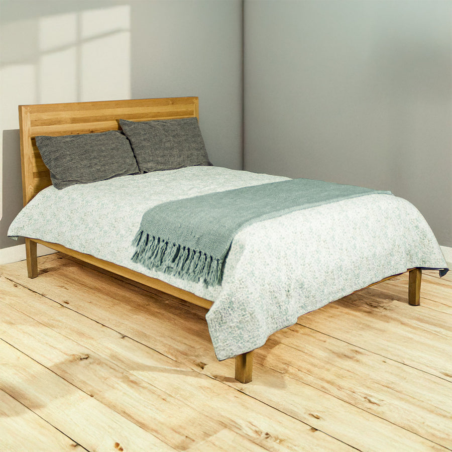 The front of the Ormond Oak Double Bed Frame with sheets and pillows on top.