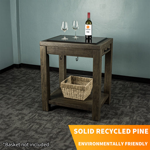 Front view of the Stonemill Recycled Pine Granite Workbench. There are two glasses and a bottle on the granite top, and a woven basket on the lower shelf.