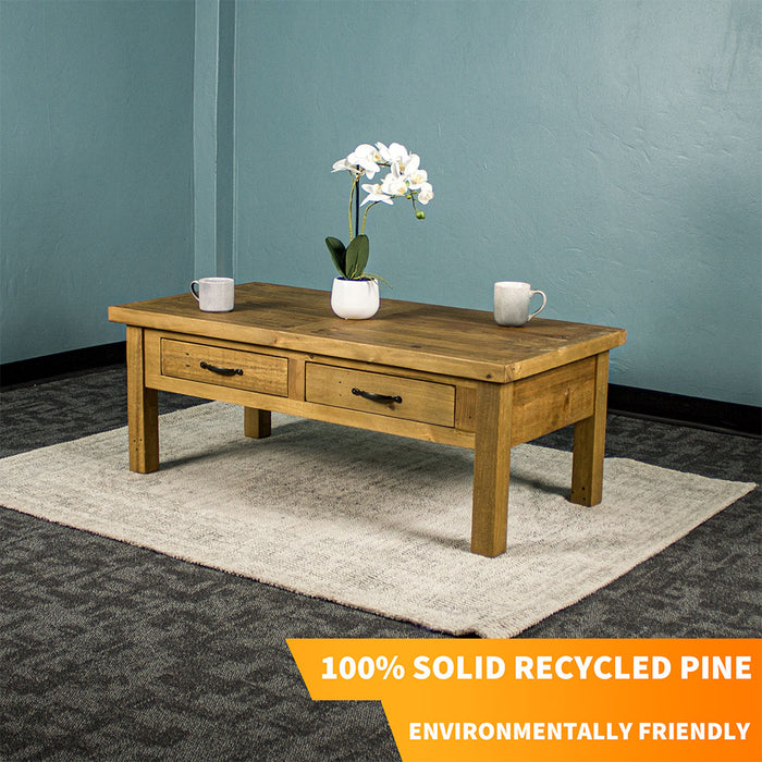 Front view of the Ventura Recycled Pine Coffee Table sitting on a rug. There are two coffee mugs and a pot of white flowers on top.