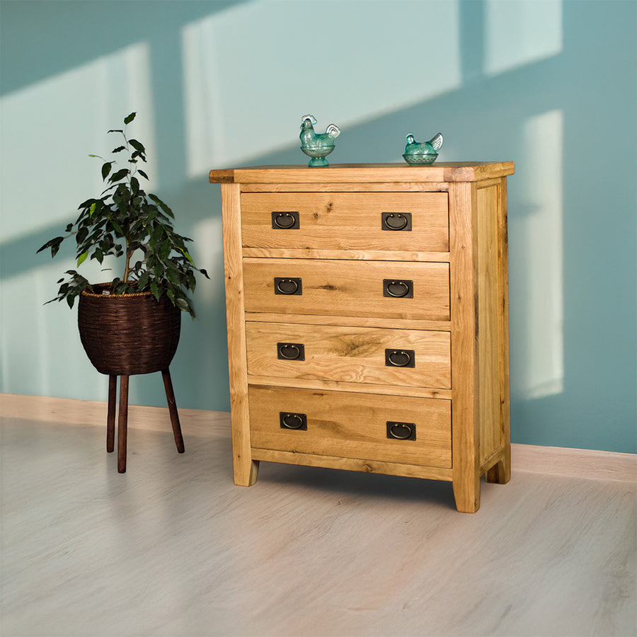 The front of the Yes Four Drawer Oak Tallboy. There are two blue glass ornaments on top and a free standing potted plant next to the tallboy.