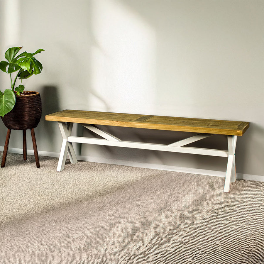 The white and rimu-stained top Byron Recycled Pine Bench with cross legs and a support bar through the middle.