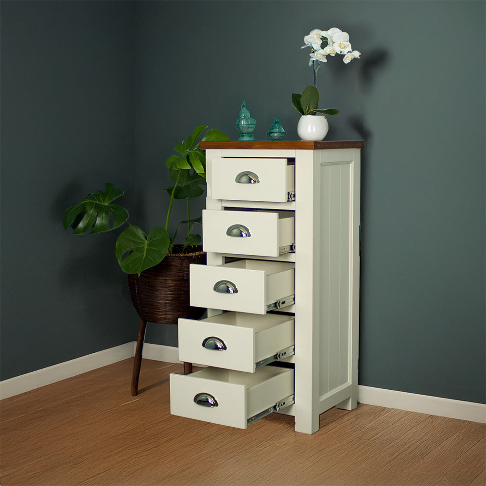 The front of the Alton 5 Drawer Lingerie Chest with its drawers open. There is a free standing potted plant next to it. There are two blue glass ornaments and a small pot of white flowers on top.