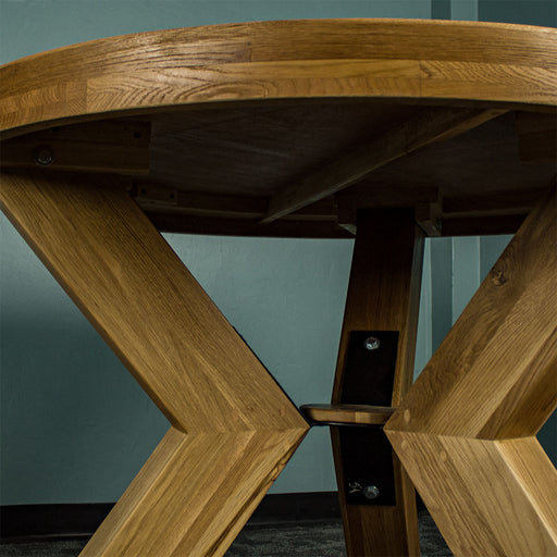 Underneath the Amstel Round Oak Dining Table, showing the legs securely in place.