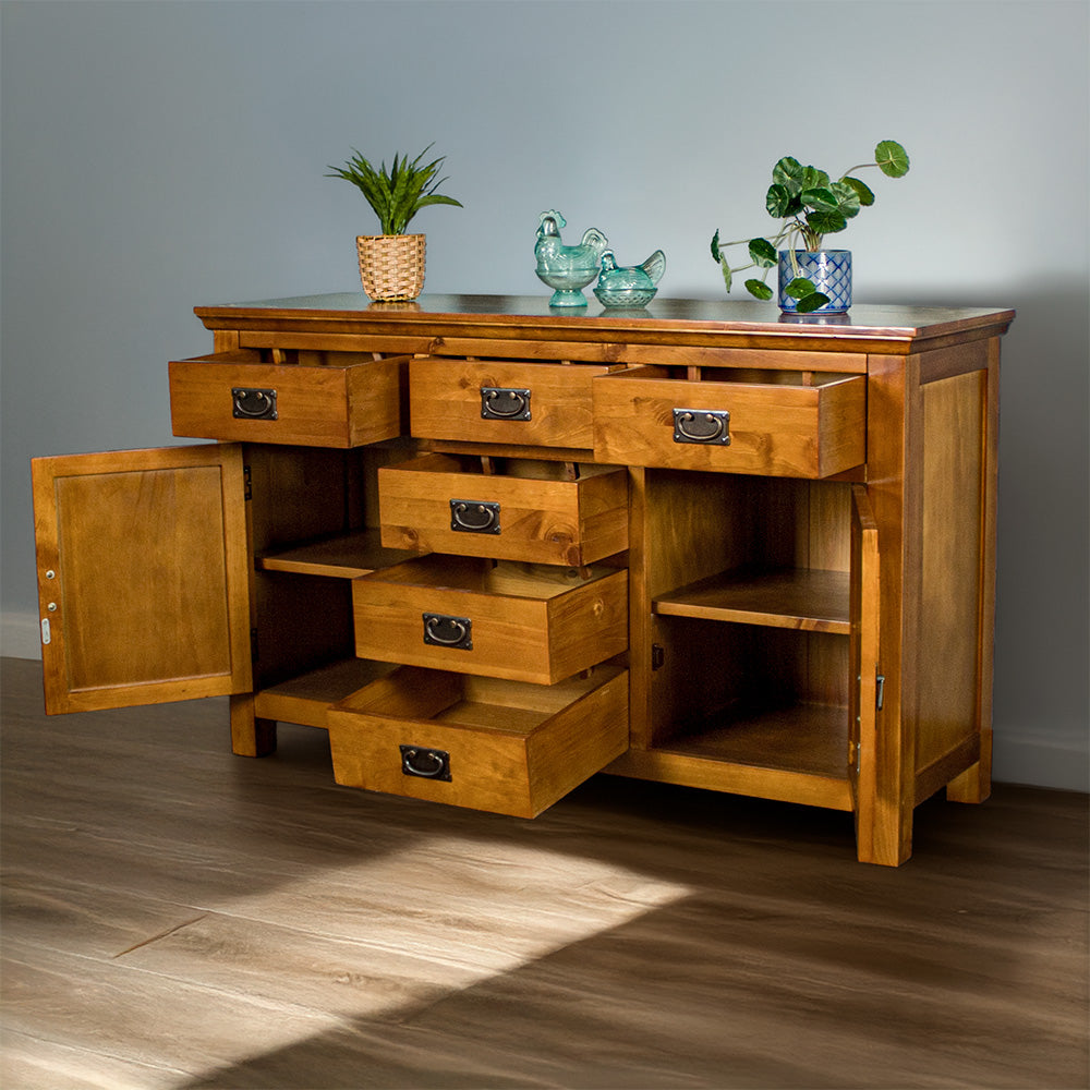 Front view of the Montreal Rimu Stained Buffet/Sideboard with its drawers and doors open. There are two blue glass ornaments and two potted plants on top.