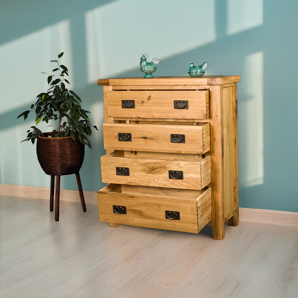 The front of the Yes Four Drawer Oak Tallboy with its drawers open. There are two blue glass ornaments on top and a free standing potted plant next to the unit.