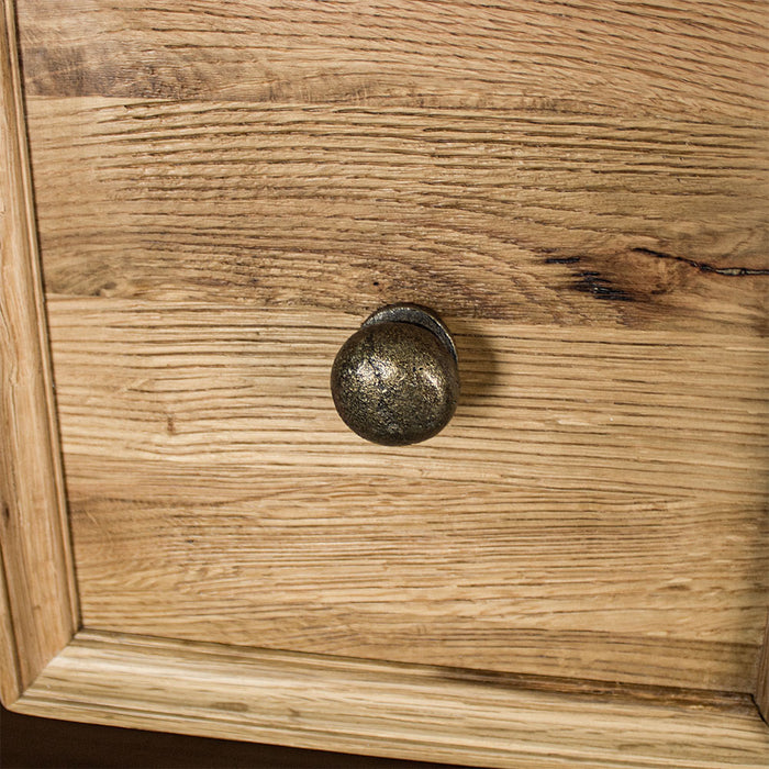 A close up of the brushed brass handle on the drawers of the Versailles Oak 7 Drawer Chest.