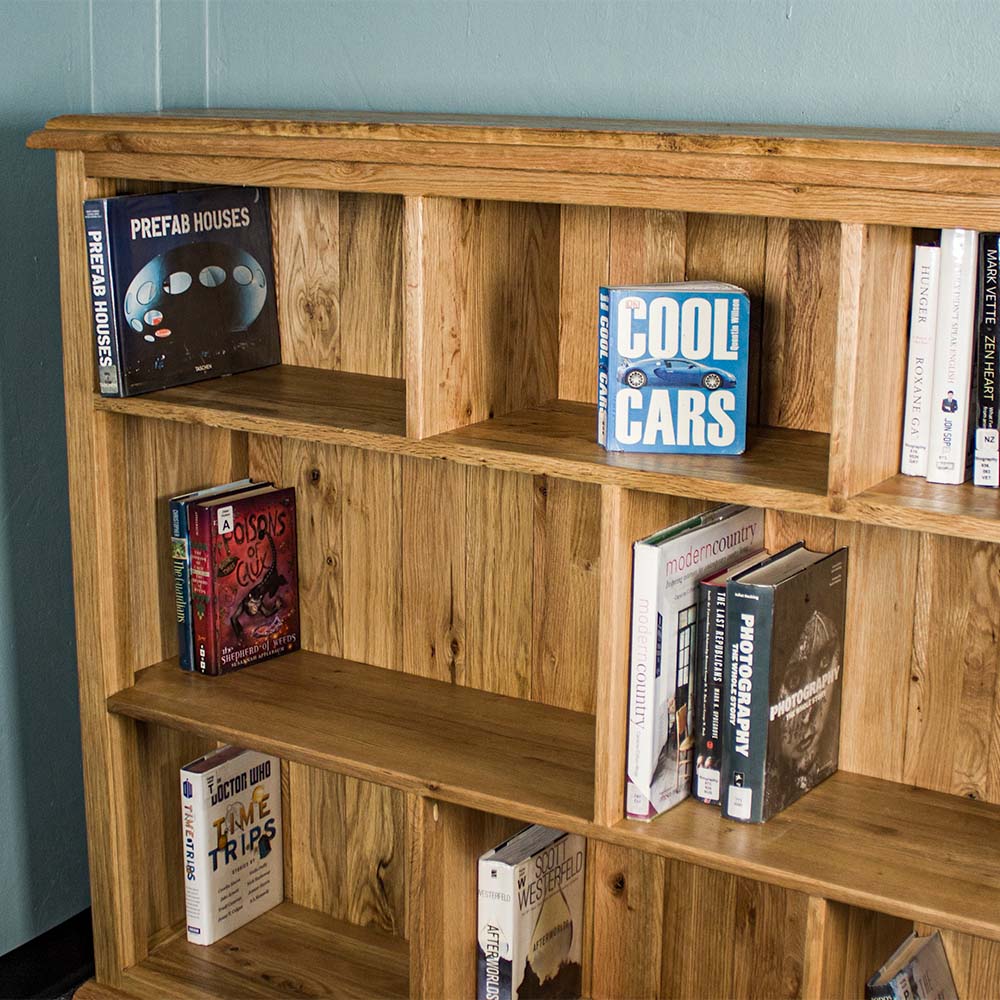 Half of the Versailles Outback Oak Three Level Bookcase, showing off the middle and top shelves. There are various books on the shelves.