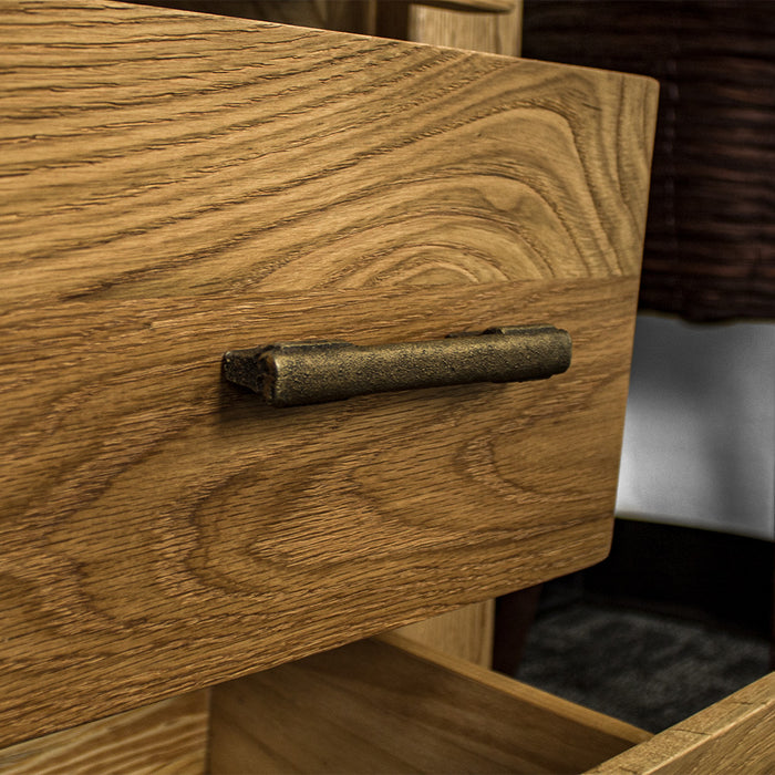 A close up of the brushed brass coloured handle on the Camden 3 Drawer White Oak Bedside Table.