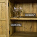 A view of the larger shelf on the Cairns Recycled Pine Buffet. There are three wine glasses on the shelf.