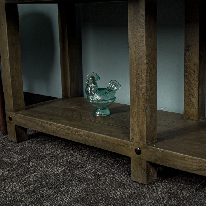 Close up of the lower shelf of the Stonemill Recycled Pine Hall Table. There is a blue glass chicken ornament sitting on it.