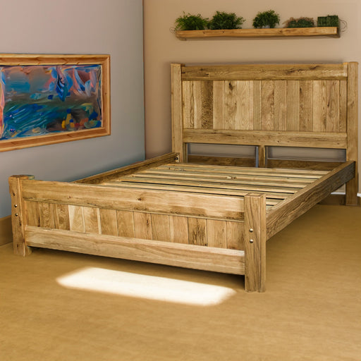 An overall view of the Amalfi Super King Oak Bed Frame in a bedroom. There is a painting on the wall and plants on a free hanging shelf above the bed.