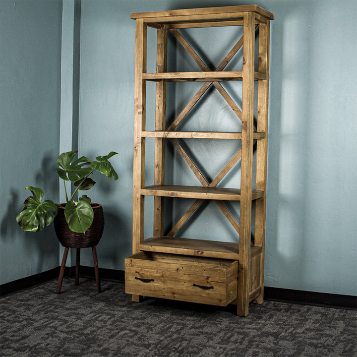 The light brown Ventura Recycled Pine Bookcase with its drawer open, and a standing potted plant next to it.