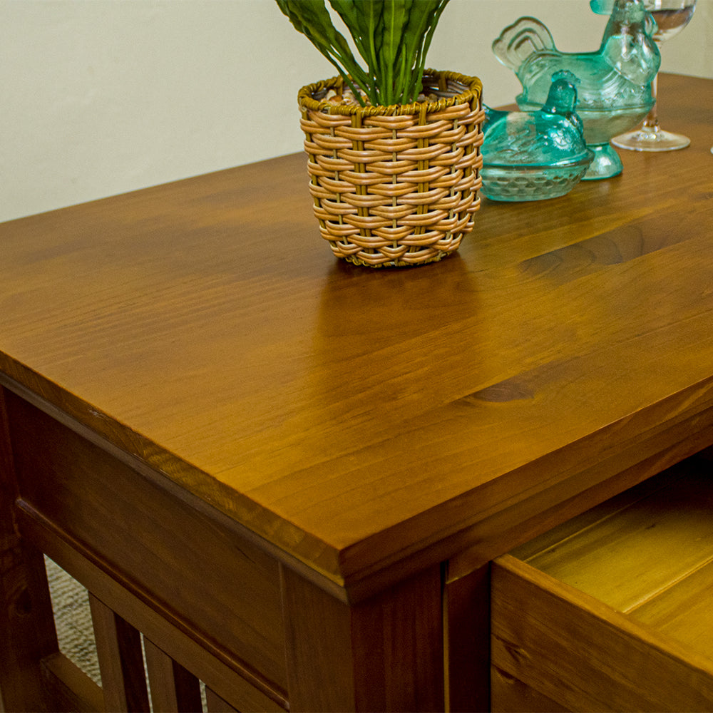 A close up of the top of the Montreal Coffee Table with 2 Drawers, showing the wood grain and colour. There is a potted plant and two blue glass ornaments on top.