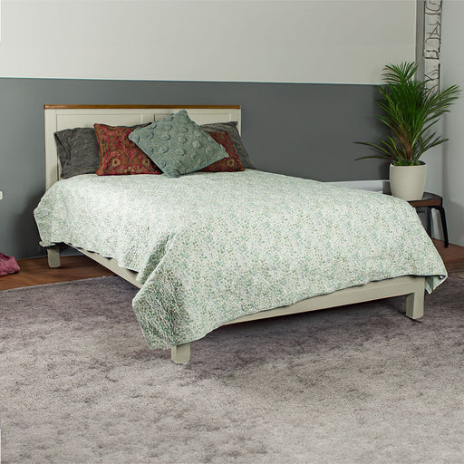 An overall view of the Alton Double Slat Bed-Frame in a bedroom. It is covered in a green/blue blanket, with multiple pillows on top. There is a potted plant next to the bed.