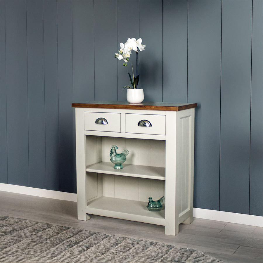 Front view of the Alton Hall Table with 2 Drawers. There is a flower pot on top and two blue glass ornaments on each of the shelves.