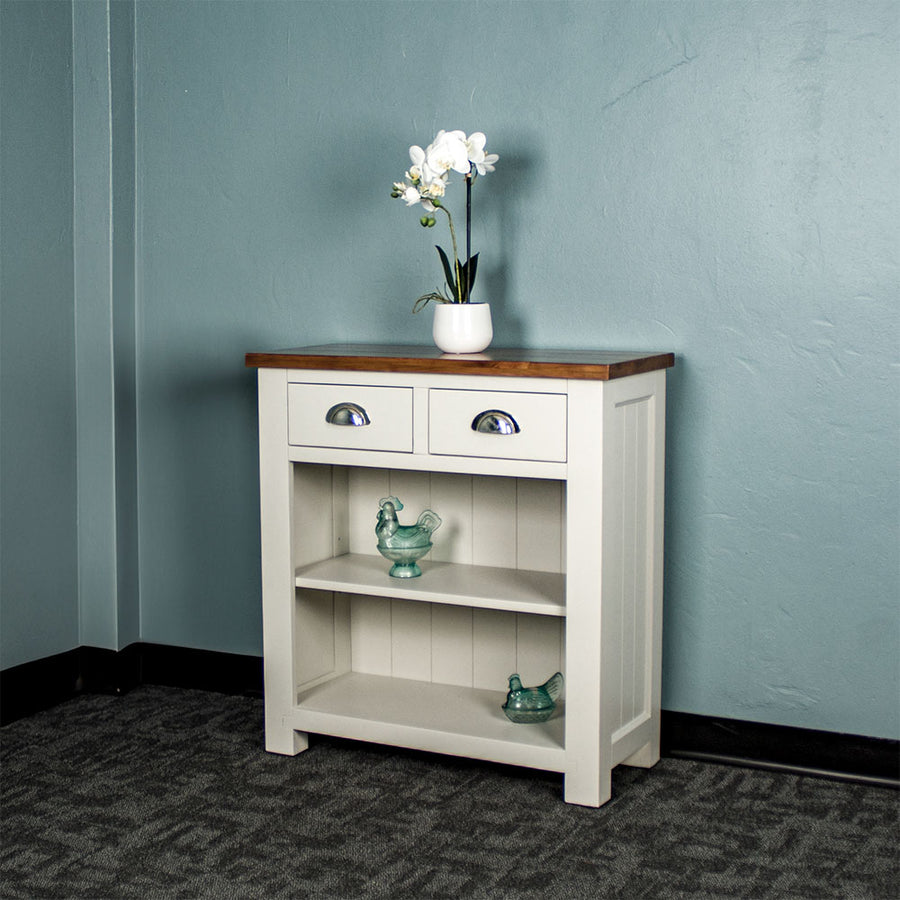 Front view of the Alton Hall Table with 2 Drawers. There is a flower pot on top and two blue glass ornaments on each of the shelves.