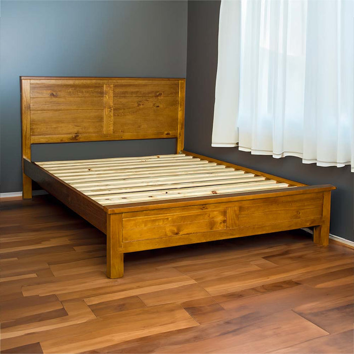 The front of the Alton Rimu-stained NZ Pine Queen Bed Frame in a bedroom with gray walls and white curtains. There are wooden floorboards.