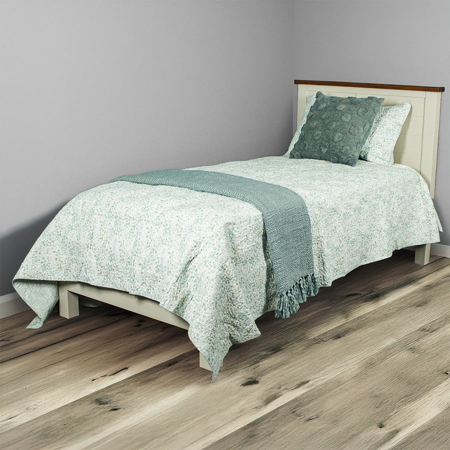 An overall view of the Alton Single NZ Pine Slat Bed Frame, covered in blankets and pillows.