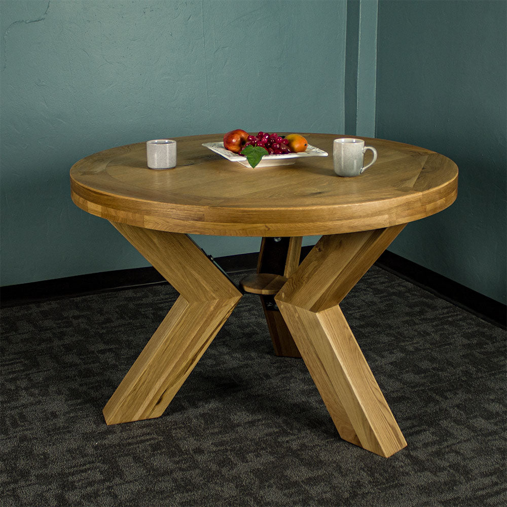 Front of the smooth natural oak stained Amstel Round Oak Dining Table with two coffee mugs and a fruit platter on top.