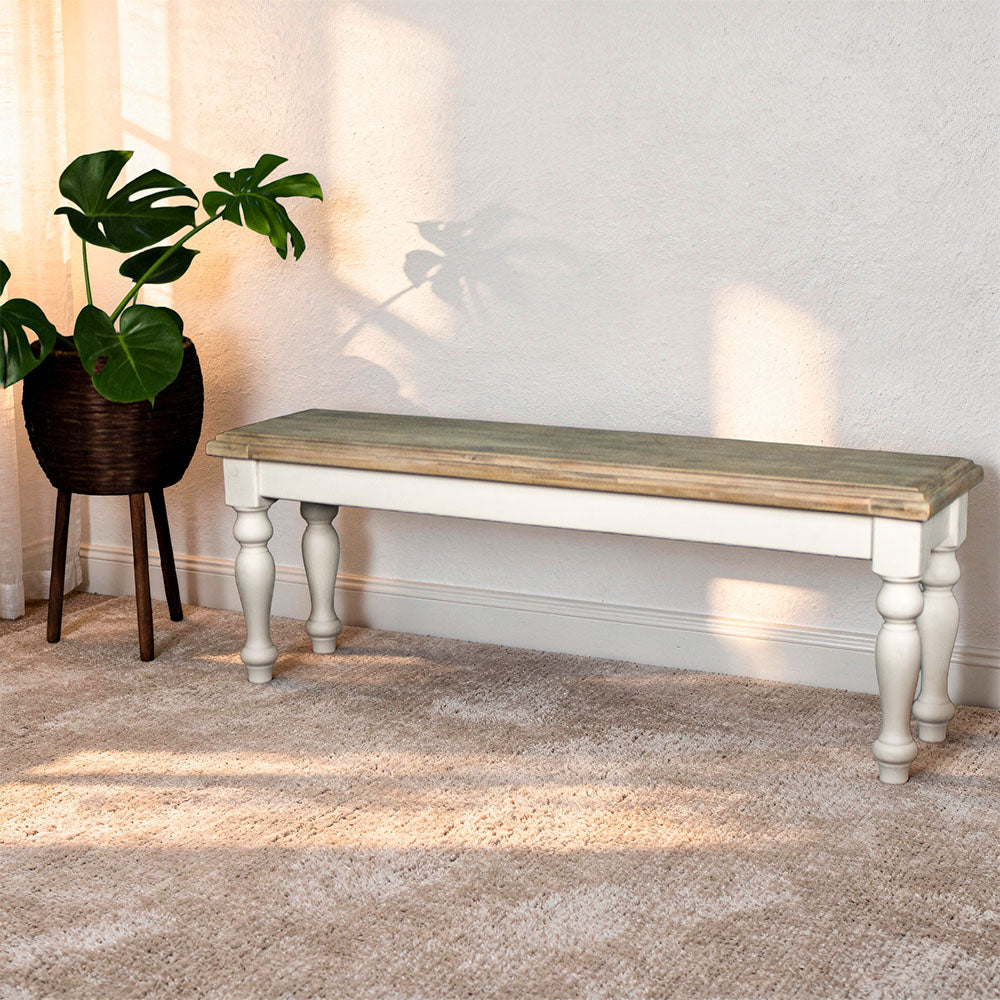 An overall view of the Biarritz 1.4m Bench. There is a free standing potted plant next to it.