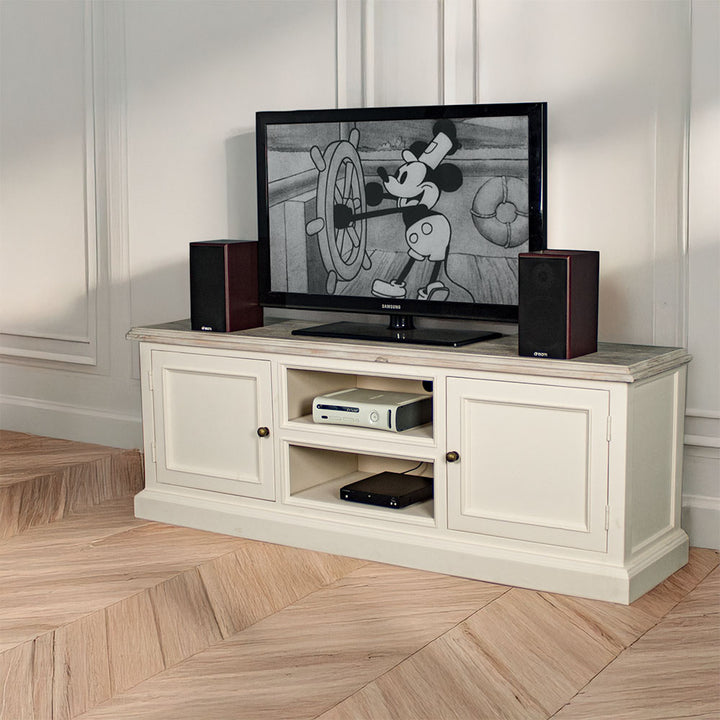 The front of the Biarritz Entertainment Unit with a large TV on top and two speakers on either side. There is a game console and a DVD player on the top and bottom shelves. There is a free standing potted plant next to the TV stand.