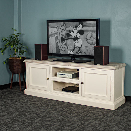 The front of the Biarritz Entertainment Unit with a large TV on top and two speakers on either side. There is a game console and a DVD player on the top and bottom shelves. There is a free standing potted plant next to the TV stand.