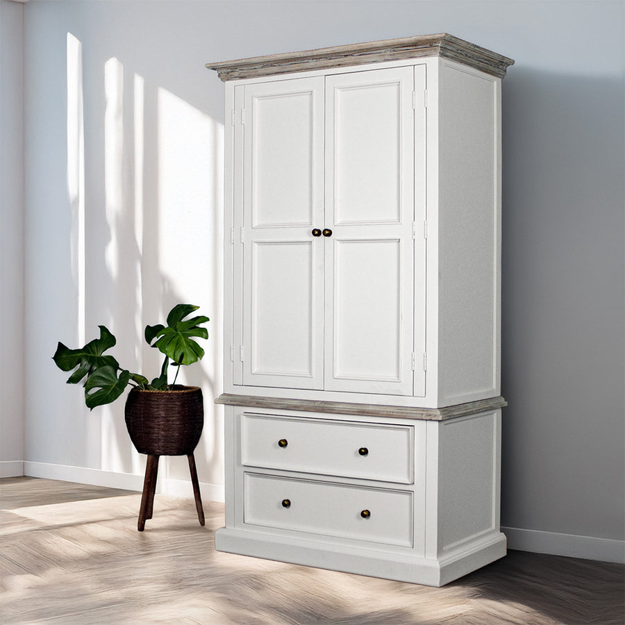 An overall view of the Biarritz Two-piece Wardrobe. There is a free standing potted plant next to it.