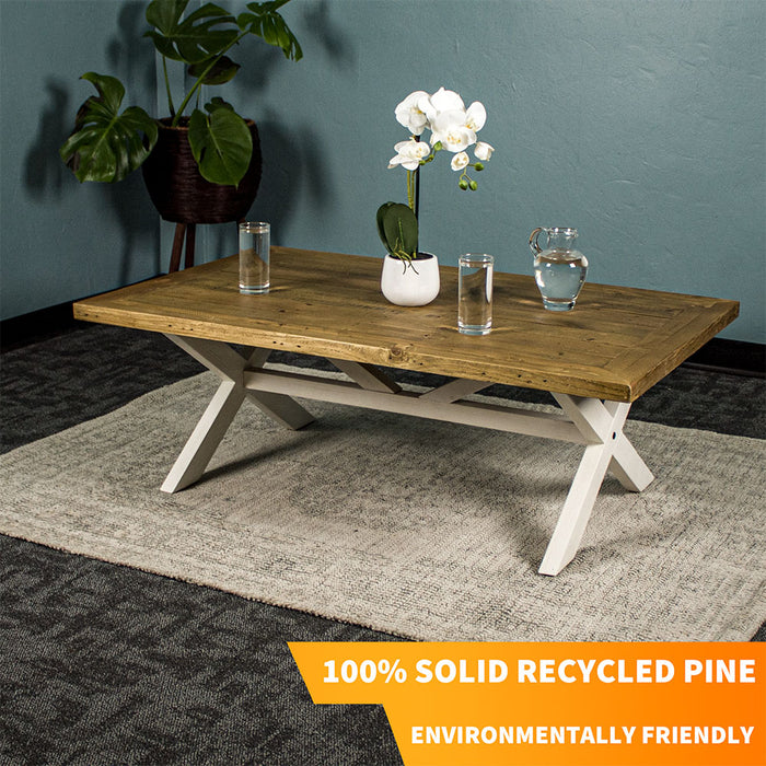 Front view of the Byron Recycled Pine Coffee Table. There are two glasses of water and a pitcher of water on top, as well as a small pot of white flowers.