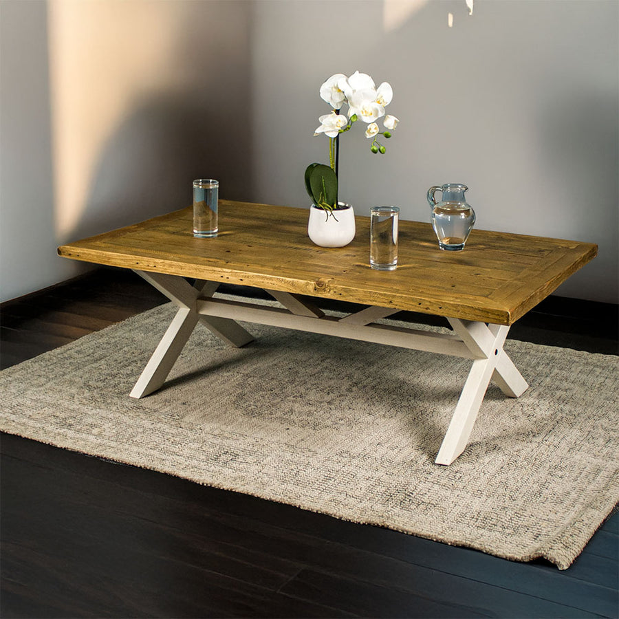 Front view of the Byron Recycled Pine Coffee Table. There are two glasses of water and a pitcher of water on top, as well as a small pot of white flowers.
