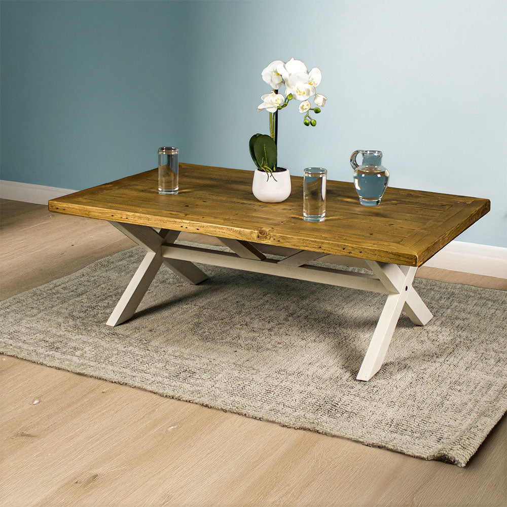 Front view of the Byron Recycled Pine Coffee Table. There are two glasses of water and a pitcher of water on top, as well as a small pot of white flowers.
