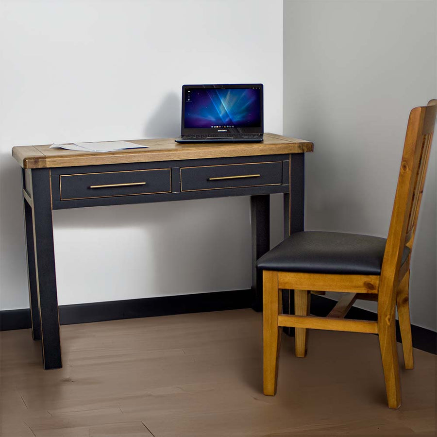 The front of the Cascais Black Desk. There is a laptop and papers on top of the desk and a upholstered pine dining chair in front of the desk.