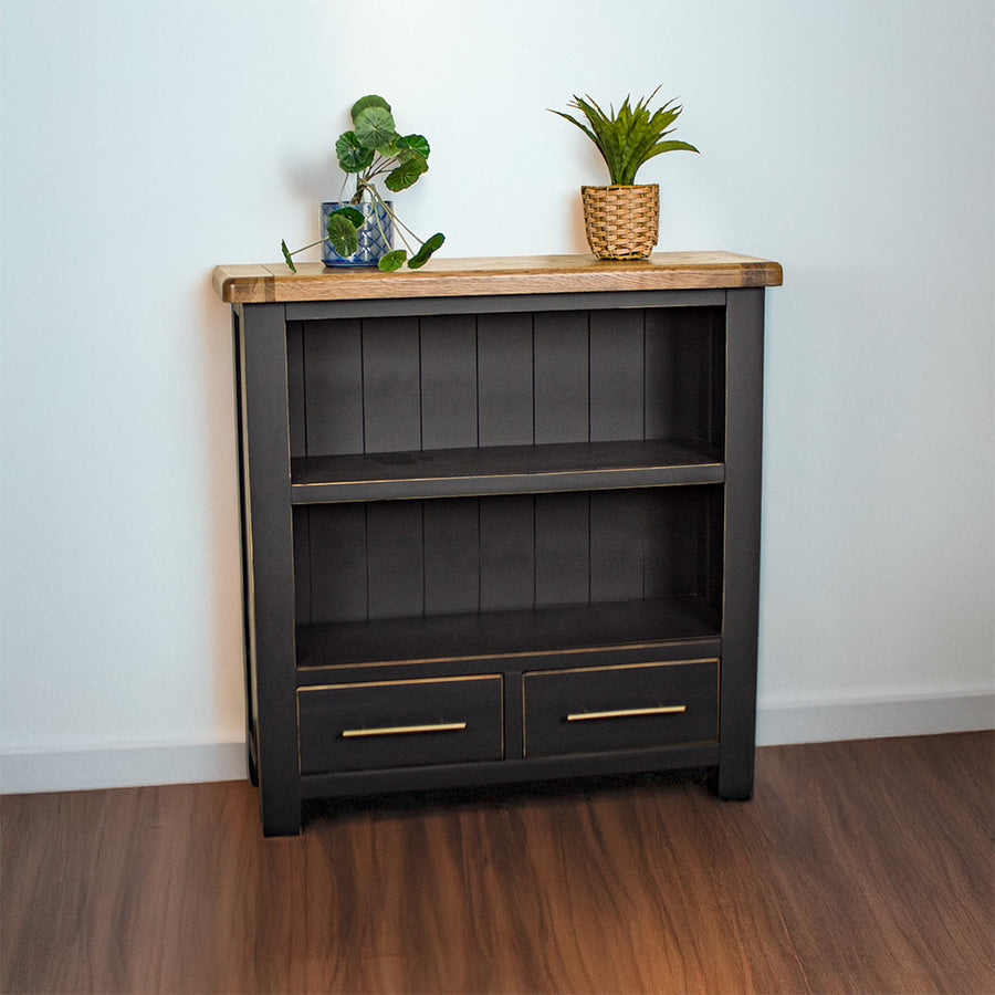 The front of the Cascais Oak Low Bookcase. There are two potted plants on top.