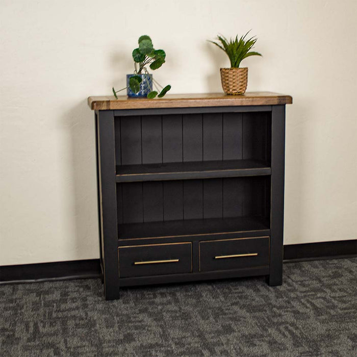 The front of the Cascais Oak Low Bookcase. There are two potted plants on top.