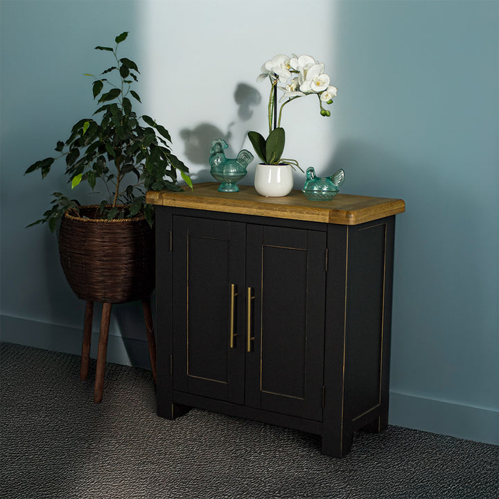 The front of the Cascais Oak-Top Small Sideboard. There are two blue glass ornaments on top with a pot of white flowers in between. 