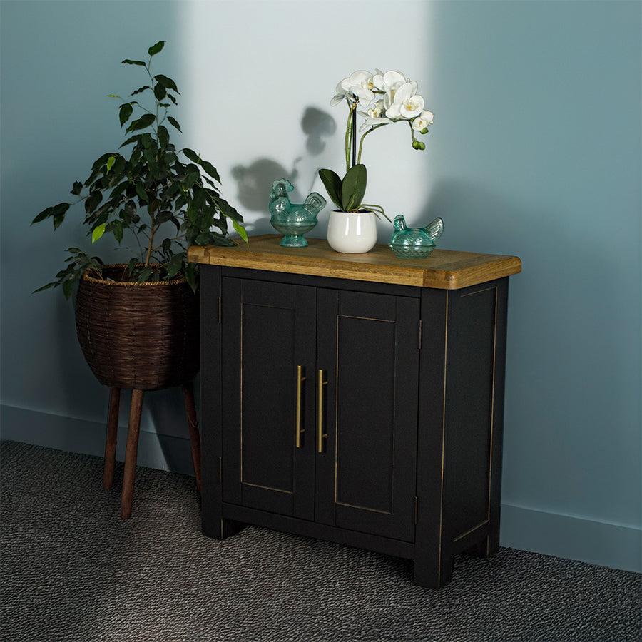 The front of the Cascais Oak-Top Small Sideboard. There are two blue glass ornaments on top with a pot of white flowers in between. 