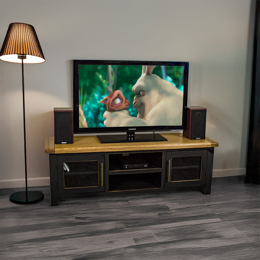 An overall view of the Cascais 2 Door Medium Entertainment Unit. There is a large TV on top with two speakers on either side. There is a DVD player on the top shelf in the middle of the unit.