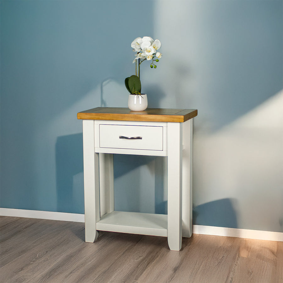 Front of the white Felixstowe Small Pine Hall Table. There is a small pot of white flowers on top.