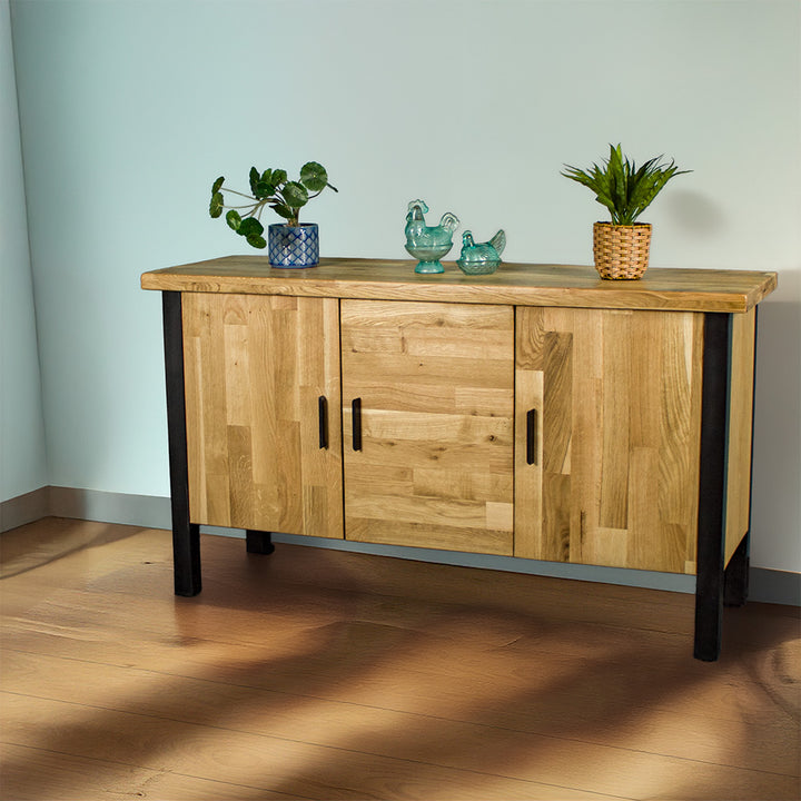 The front of the Golden Gate Three Door Oak Buffet. There are two potted plants on top and two blue glass ornaments in the middle.