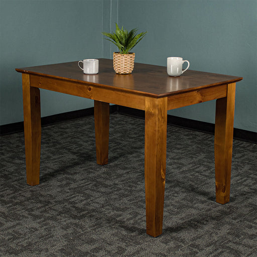 An overall view of the Hamilton Dining Table with Rimu Finish (1200mm), with a potted plant on top and two coffee mugs.