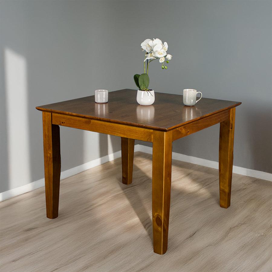 Front of the Hamilton Square Pine Dining Table (1m). There are two coffee mugs and a pot of flowers on top.