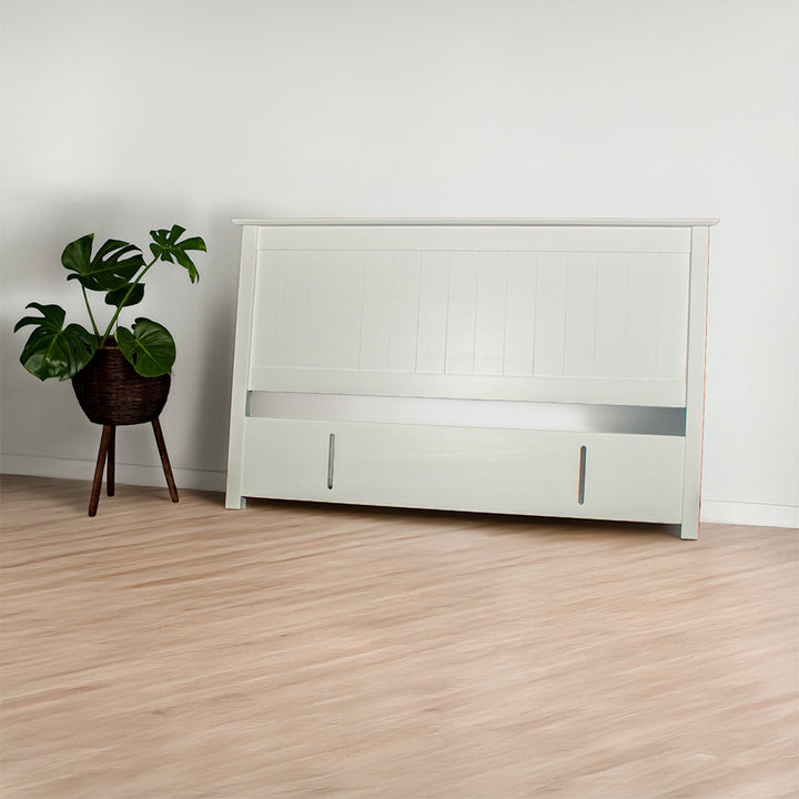 The front of the Hamilton King Size Pine Headboard. There is a potted plant next to the headboard.