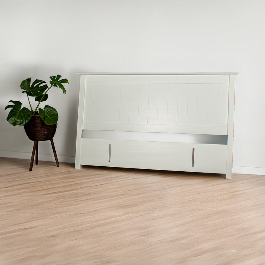 The front of the Hamilton King Size Pine Headboard. There is a potted plant next to the headboard.