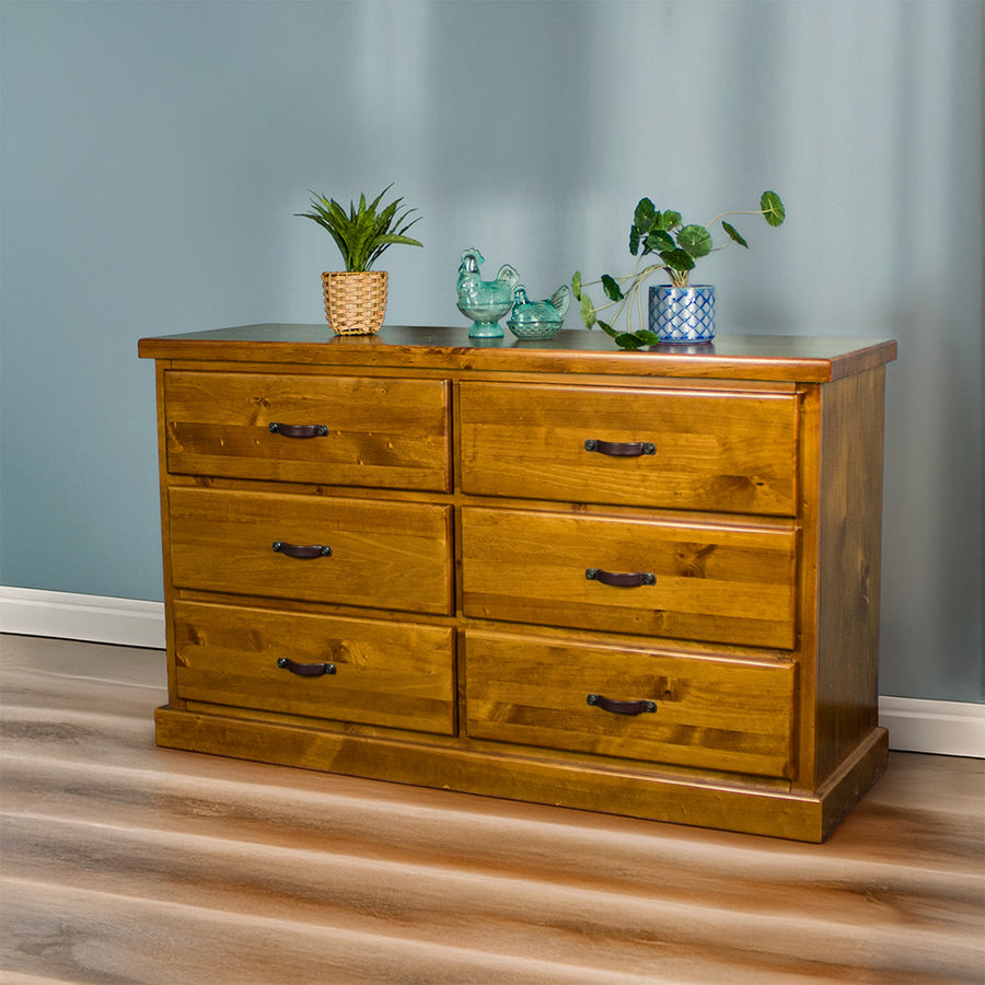 Front view of the Jamaica 6 Drawer Pine Lowboy, there are two potted plants and two blue glass ornaments on top.