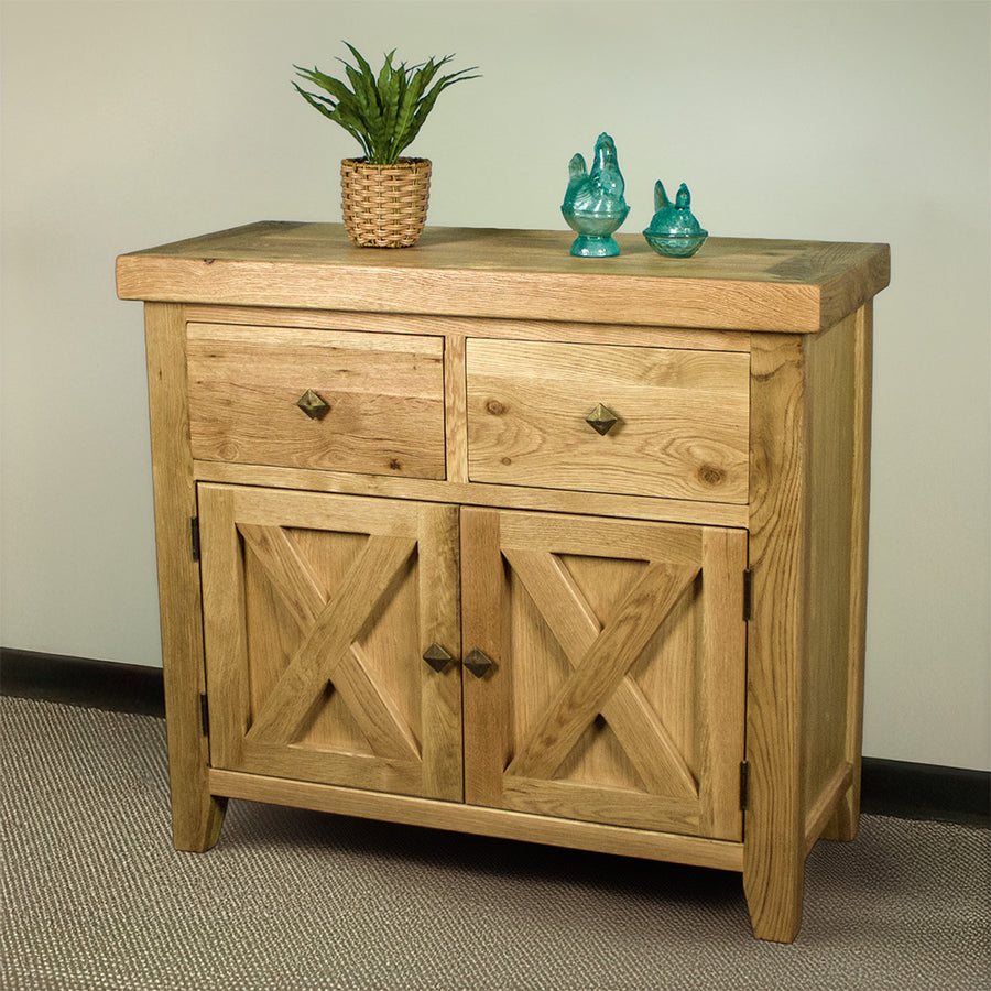 The front of the Maximus Small Oak Buffet. There is a potted plant and two blue glass ornaments on top.
