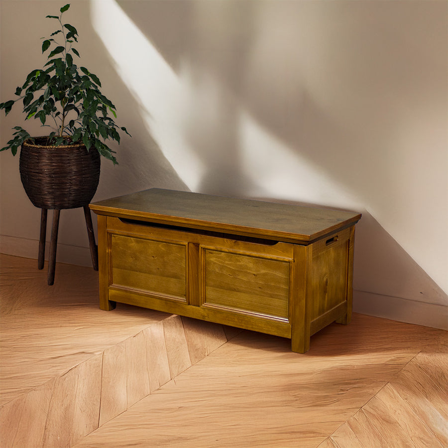 The front of the Montreal Pine Blanket Box. There is a tall free standing potted plant next to it.